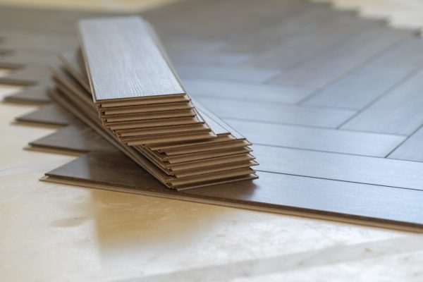Close-up of laminate flooring installation in a modern apartment. Worker placing wood planks for a smooth and polished home finish