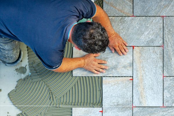 Tiler carefully lays every single tile with the help of a wire to respect the geometry of the flooring.